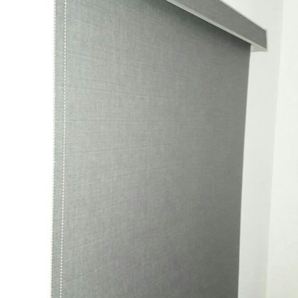 Tienda de persianas, Persiana gris enrollable traslucida de dimensiones 120 x 120 cm con pared blanca de fondo inclinada hacia la derecha