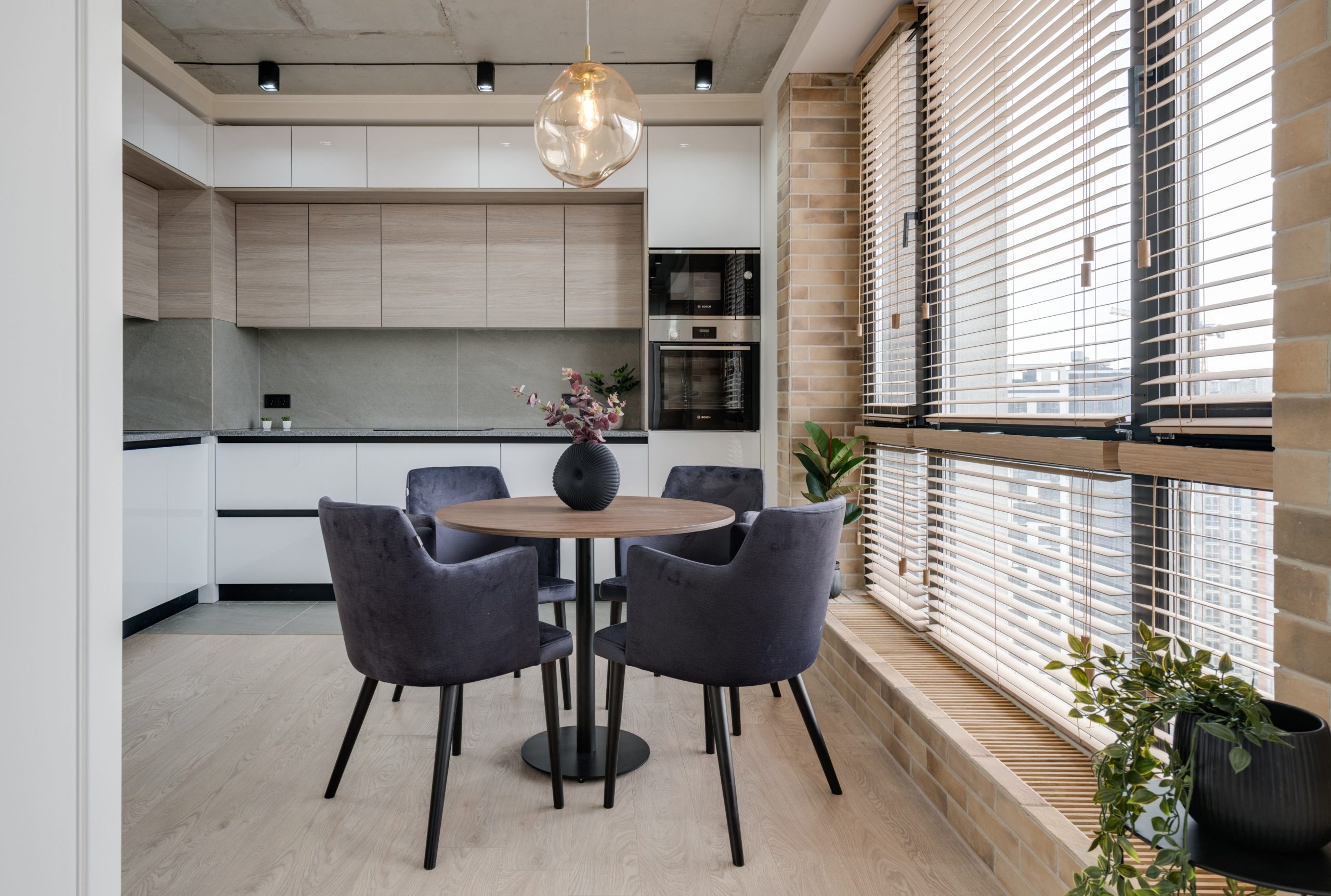 Persianas monterrey; modelo horizontal de PVC colocado en ventanales que van del techo al piso que permiten iluminar cocina integral y ante-comedor de departamento moderno.