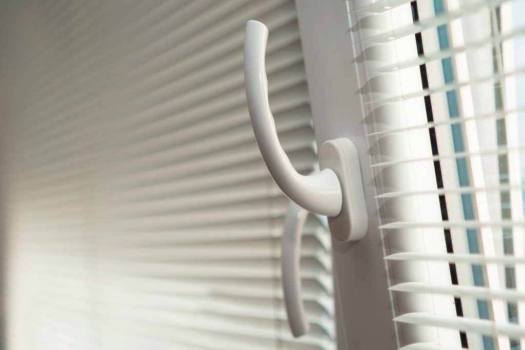 Persianas de PVC en el marco de una ventana de plástico abierta para ventilación.